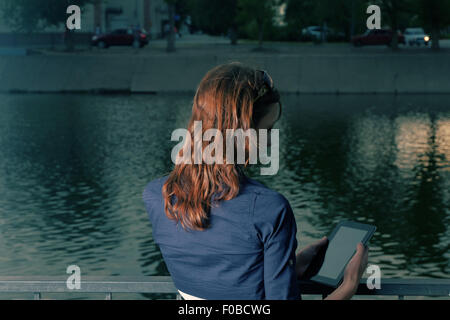 Redhair studente lavoro femminile computer tablet vicino al lago nel parco del campus Foto Stock