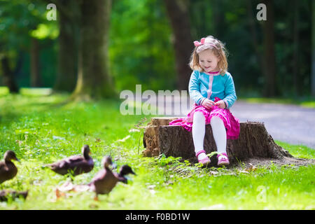 Bambina anatra di alimentazione in un parco d'estate. Alimentazione per bambini uccelli e animali. Bambino che gioca all'esterno. Foto Stock