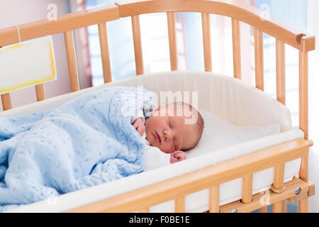 Neonato ragazzo nel letto. Il nuovo nato il bambino dorme sotto una maglia blu coperta. I bambini dormono. Biancheria da letto per bambini. Foto Stock