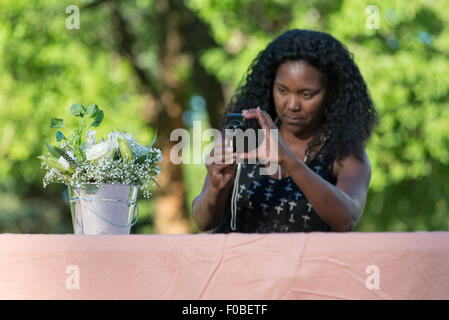 Donna di fotografare la benna di flowerw a un matrimonio, Oregon. Foto Stock