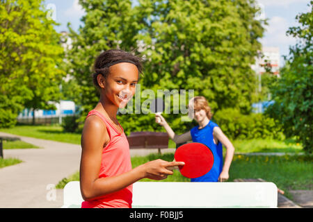 Ragazza africana giocando a ping pong con ragazzo al di fuori Foto Stock