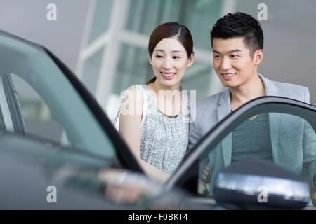 Coppia giovane cercando nuove auto in showroom Foto Stock