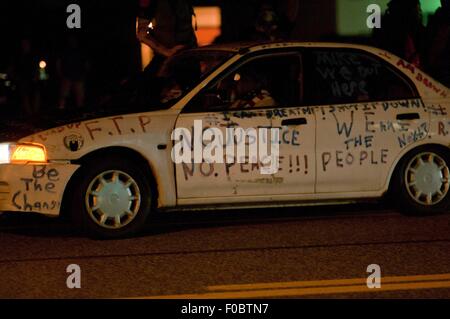 Ferguson, STATI UNITI D'AMERICA. 11 Ago, 2015. Una vettura dipinta con slogan è visto nel corso di una manifestazione in Ferguson, gli Stati Uniti, il 11 agosto, 2015. Le proteste dell'anniversario della ripresa di disarmato 18-anno-vecchio Michael Brown sono state estese per una seconda giornata di martedì in Ferguson. Lo stato di emergenza è stato dichiarato per la città di Ferguson il lunedì a seguito di scontri tra polizia e manifestanti domenica notte. Credito: Egli Xianfeng/Xinhua/Alamy Live News Foto Stock