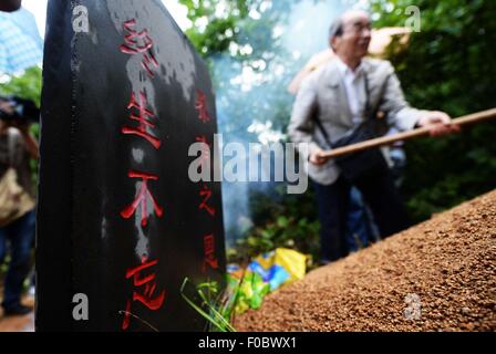 Mudanjiang City in Cina. 11 Ago, 2015. Il 73-anno-vecchio Yohachi giapponese Nakajima, un 'orfana di guerra' sinistra in Cina dopo la seconda guerra mondiale, spazzano la tomba dei suoi genitori adottivi nella città di Mudanjiang, a nord-est della Cina di Provincia di Heilongjiang, 11 Agosto, 2015. Nakajima è andato a nord-est della Cina di Heilongjiang provincia nel 1942 con la sua famiglia come membri di 'Giapponese gruppo di coloni' quando lui era solo un bambino di un anno. Ma nel 1945, quando il Giappone militaristico si arresero alla fine della Seconda Guerra Mondiale è stato lasciato in Cina soltanto. Credito: Xinhua/Alamy Live News Foto Stock