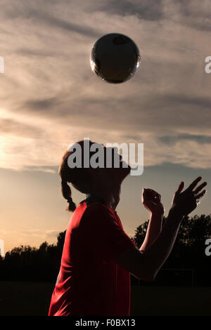 Vista laterale del giocatore di calcio voce palla in campo Foto Stock