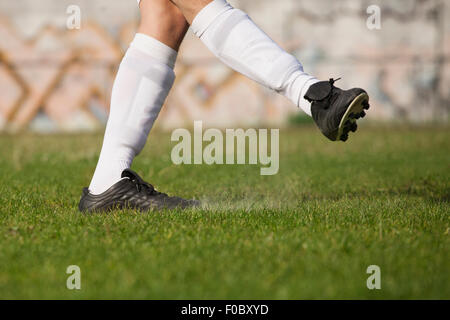 Sezione bassa del giocatore di calcio calci sul campo erboso Foto Stock