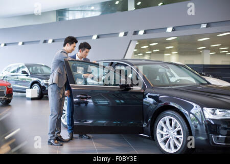 Giovane imprenditore la scelta di auto in showroom Foto Stock