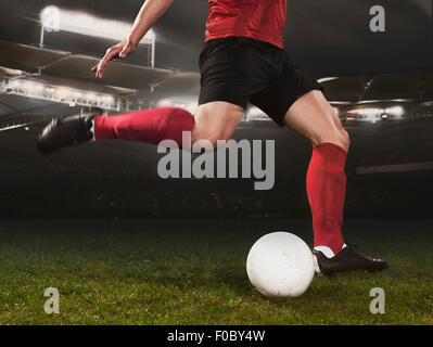 Sezione bassa del giovane giocatore di calcio calci palla sul campo Foto Stock