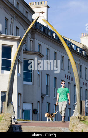 Uomo che cammina il suo cane attraverso il famoso osso di balena arch West Cliff Whitby North Yorkshire Foto Stock