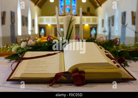 Aprire la Bibbia e fiori matrimonio sull'altare nella chiesa cattolica. DOF poco profondo Foto Stock