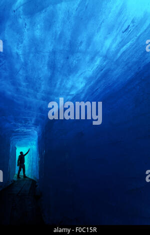 Silhouette uomo nella caverna di ghiaccio. Ghiacciaio del Rodano, Svizzera, Europa. Foto Stock