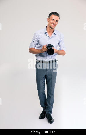 A piena lunghezza Ritratto di un felice giovane uomo tenere la fotocamera isolato su uno sfondo bianco Foto Stock