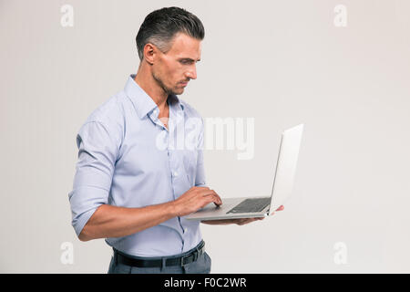 Ritratto di un uomo bello utilizzando computer portatile isolato su sfondo bianco Foto Stock