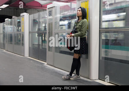 La donna sta nella metropolitana appoggiata contro la barriera Foto Stock