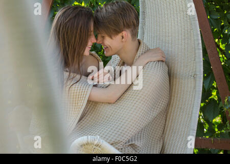 Romantico coppia giovane avvolto in un lenzuolo sul sedia appesi all'aperto Foto Stock