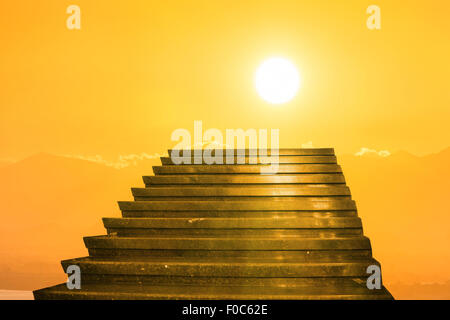 Scala verso il cielo. Le scale verso il sole sul arancione tramonto con le nuvole Foto Stock