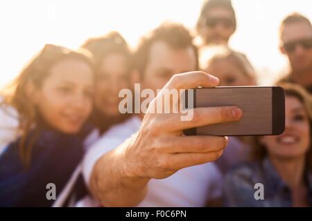 Gruppo di amici prendendo selfie sulla spiaggia Foto Stock