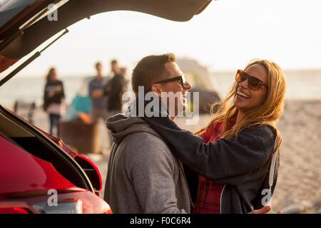 Giovane rilassante dietro il veicolo sulla spiaggia Foto Stock