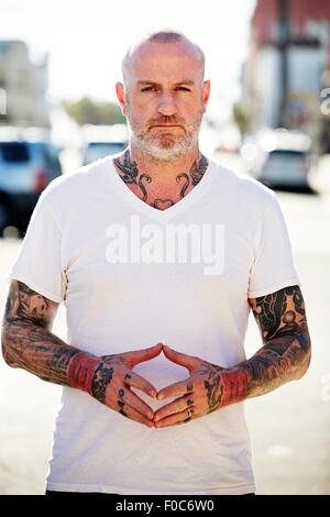 Uomo maturo con tatuaggi sulle braccia e collo Foto Stock