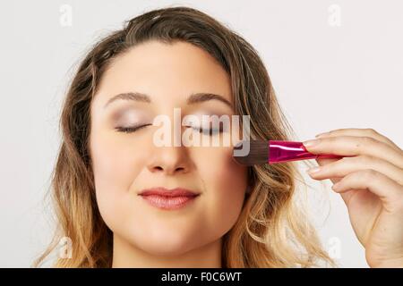 Giovane donna utilizzando blusher pennello Foto Stock