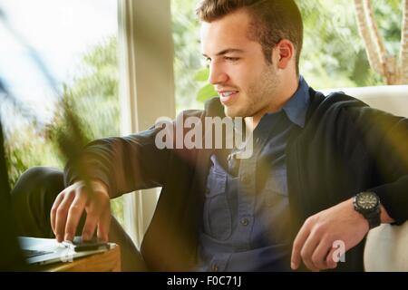 Ritratto di uomo seduto sul pavimento con il computer portatile Foto Stock