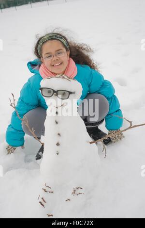 Ragazza giovane edificio pupazzo di neve Foto Stock