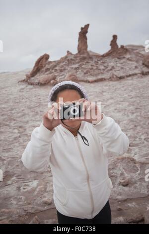 Giovane ragazza tenendo fotografia utilizzando la fotocamera e la Valle della Luna, San Pedro, Atacama, Cile Foto Stock