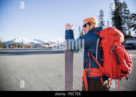 Giovane maschio sciatore in parcheggio con distante Snow capped Mount Baker, Washington, Stati Uniti d'America Foto Stock