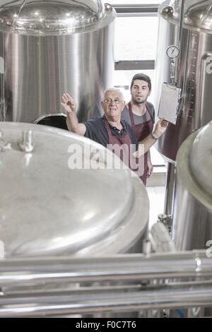 Produttori di birra in birreria accanto a serbatoi in acciaio inox Foto Stock