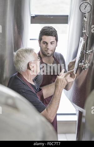 Produttori di birra in birreria accanto a serbatoi in acciaio inox Foto Stock