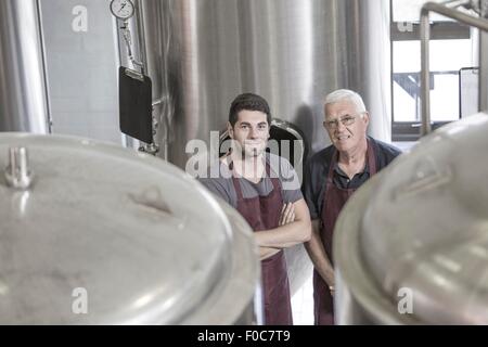 Produttori di birra in birreria accanto a serbatoi in acciaio inox Foto Stock