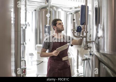 Produttori di birra birreria in piedi accanto a serbatoi in acciaio inox Foto Stock