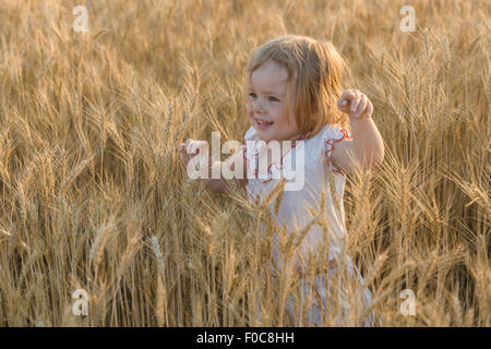 Felice ragazza camminare nel campo di grano Foto Stock