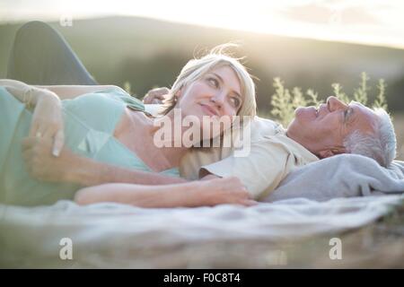 Coppia matura giacente insieme sulla coperta all'aperto Foto Stock