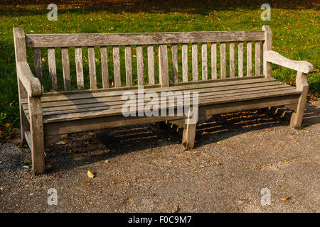Panca in legno nel parco che è vuoto. Weathered look. Sole splende Foto Stock