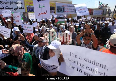 Amman, Giordania. 12 Ago, 2015. Palestinesi Gridare slogan e tenere premuto cartelli contro l'Ente soccorso e lavori delle Nazioni Unite (UNRWA) in Wehdat Al campo profughi palestinese di Amman, Giordania, Agosto 12, 2015. Migliaia di studenti palestinesi, gli insegnanti e i lavoratori hanno protestato contro la riduzione dei servizi ai rifugiati palestinesi in Giordania. Credito: Mohammad Abu Ghosh/Xinhua/Alamy Live News Foto Stock