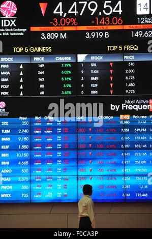 Jakarta, Indonesia. 12 Ago, 2015. Un membro del personale cammina davanti ad una schermata che mostra informazioni di borsa in Indonesia Stock Exchange di Jakarta, Indonesia, Agosto 12, 2015. © Zulkarnain/Xinhua/Alamy Live News Foto Stock