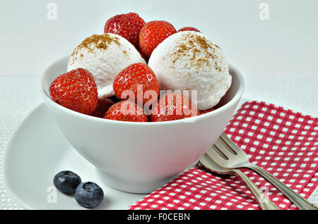 Chiudere fino a un bianco ciotola con gelato alla vaniglia e fragole e mirtilli, macro, full frame, orizzontale Foto Stock