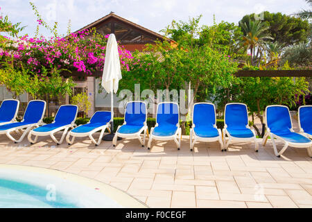 Blue lettini intorno a una piscina in albergo Foto Stock