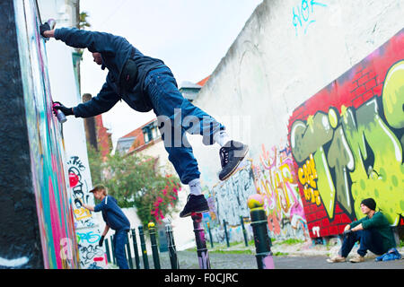 Ragazzi dipinto graffiti sul muro a Lisbona. Foto Stock