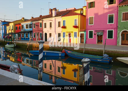 Dipinto luminosamente case di Burano si riflette in un canale laguna di Venezia Veneto Italia Europa Foto Stock