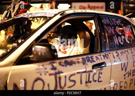 Ferguson, STATI UNITI D'AMERICA. 11 Ago, 2015. Un manifestante si copre il viso con una bandiera americana bandana durante una manifestazione in Ferguson, gli Stati Uniti, il 11 agosto, 2015. Le proteste dell'anniversario della ripresa di disarmato 18-anno-vecchio Michael Brown sono state estese per una seconda giornata di martedì in Ferguson. Lo stato di emergenza è stato dichiarato per la città di Ferguson il lunedì a seguito di scontri tra polizia e manifestanti domenica notte. © Jim Vondruska/Xinhua/Alamy Live News Foto Stock