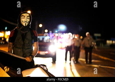 Ferguson, STATI UNITI D'AMERICA. 11 Ago, 2015. Un manifestante si allontana dai poliziotti di avvicinamento durante una manifestazione in Ferguson, gli Stati Uniti, il 11 agosto, 2015. Le proteste dell'anniversario della ripresa di disarmato 18-anno-vecchio Michael Brown sono state estese per una seconda giornata di martedì in Ferguson. Lo stato di emergenza è stato dichiarato per la città di Ferguson il lunedì a seguito di scontri tra polizia e manifestanti domenica notte. © Jim Vondruska/Xinhua/Alamy Live News Foto Stock