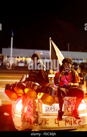 Ferguson, STATI UNITI D'AMERICA. 11 Ago, 2015. Manifestanti sedersi sul retro di un auto durante una manifestazione in Ferguson, gli Stati Uniti, il 11 agosto, 2015. Le proteste dell'anniversario della ripresa di disarmato 18-anno-vecchio Michael Brown sono state estese per una seconda giornata di martedì in Ferguson. Lo stato di emergenza è stato dichiarato per la città di Ferguson il lunedì a seguito di scontri tra polizia e manifestanti domenica notte. © Jim Vondruska/Xinhua/Alamy Live News Foto Stock