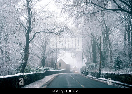 Strada che conduce verso una casa coperte di neve in campagna britannica. Foto Stock