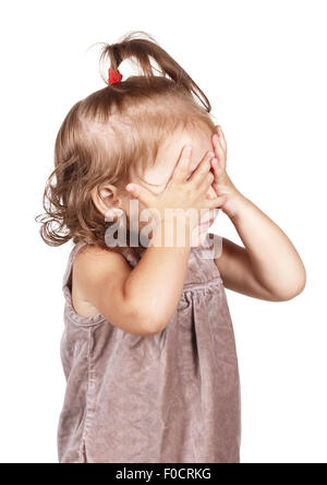 Bambina nascondere la faccia sotto le mani, isolato su bianco Foto Stock