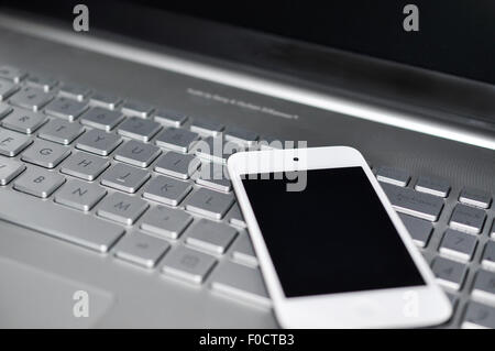 Primo piano immagine di una tastiera con un telefono che giace al di sopra di esso Foto Stock