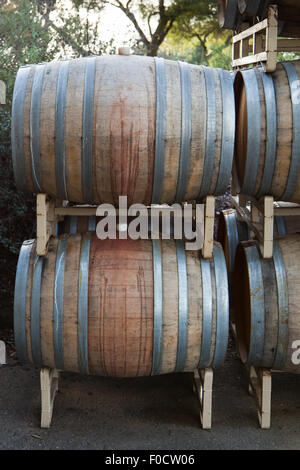 Botti da vino tinto con vino rosso impilati su rack di metallo al di fuori. Foto Stock