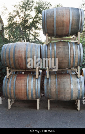 Botti da vino tinto con vino rosso impilati su rack di metallo al di fuori. Foto Stock