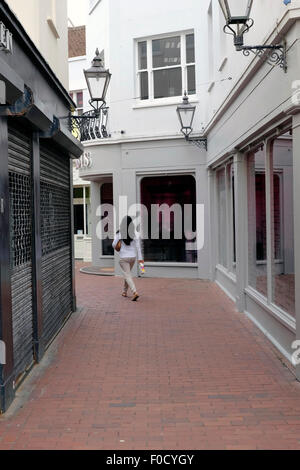 Una vista posteriore di una donna che cammina su una strada stretta Foto Stock